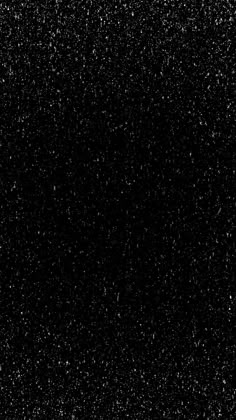 black and white photograph of snow flecks in the night sky with no clouds