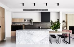 an open kitchen and dining area with marble counter tops, black chairs, and white walls