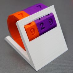 an orange, purple and white clock with numbers on the front is made out of legos