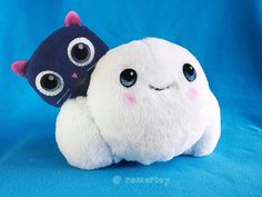 a stuffed animal with big eyes sitting next to another stuffed animal on a blue background