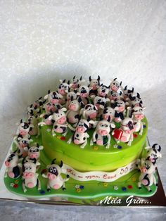 there is a cake decorated with cows on the top and bottom tier, as well as many smaller ones