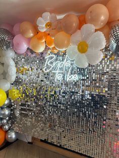 balloons and streamers are hanging from the ceiling in front of a disco ball backdrop