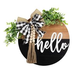 a wooden sign with the word hello on it and some greenery in front of it