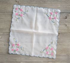 a white cloth with pink flowers on it sitting on top of a wooden table next to a pair of scissors