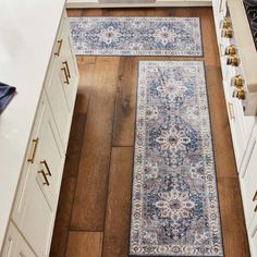 an area rug in the middle of a kitchen with white cabinets and wood flooring