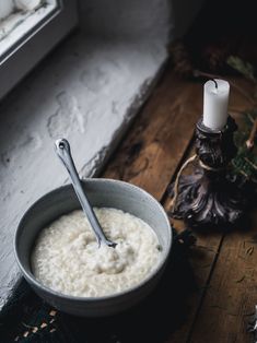 a bowl of oatmeal next to a candle