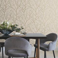 a dining table with four chairs and a vase on it, in front of a wallpapered background