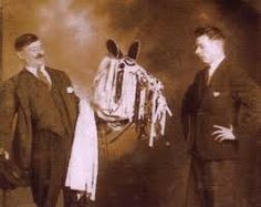 two men standing next to each other in front of a black and white photo with a horse on it's back