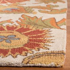 a close up of a rug on a wooden floor with an orange, yellow and blue flower design