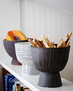 two bowls filled with sticks on top of a white shelf