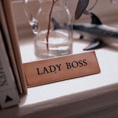 a lady boss sign sitting on top of a table next to a vase filled with flowers