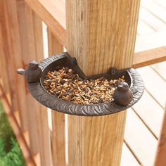 bird feeder hanging on the side of a wooden deck with birds eating out of it