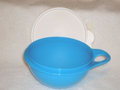 a blue bowl and white plate sitting on a tablecloth covered surface with a white cloth