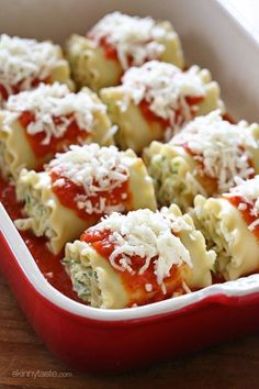 a red casserole dish filled with ravioli covered in marinara sauce and parmesan cheese