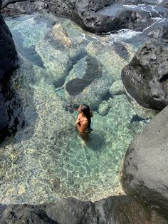 a person swimming in the water near some rocks