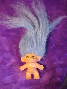 a toy troll with blue hair on a purple background