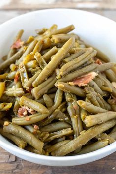 a white bowl filled with green beans and bacon