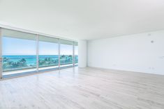 an empty living room with large windows overlooking the ocean