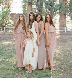 a group of women standing next to each other in front of some trees and grass