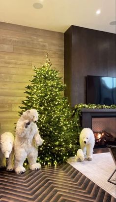 three white dogs standing in front of a christmas tree with lights on it's sides