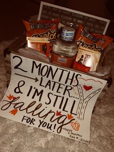 a sign that says 2 months and i'm still falling for you next to some snacks