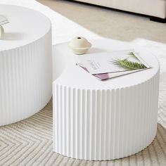 two white tables sitting on top of a carpeted floor next to each other in front of a couch