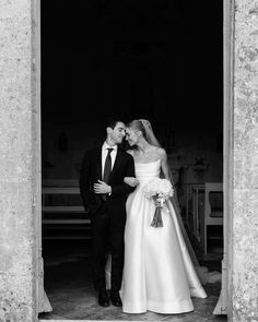 black and white photo of bride and groom kissing in church doorway with pews behind them