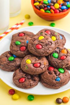 chocolate m & m cookies on a plate next to a glass of milk