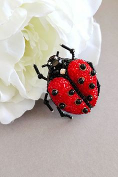 a ladybug brooch sitting on top of a white flower next to it