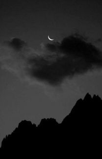 the moon is shining in the dark sky above some mountains and clouds at night time