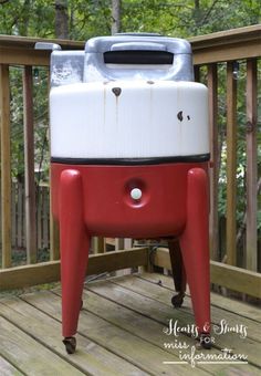 a red and white cooler sitting on top of a wooden deck