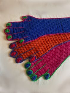 three knitted mittens sitting on top of a white surface next to each other