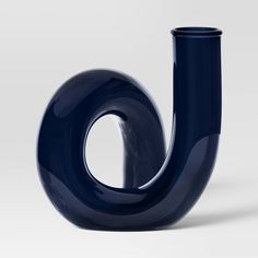 a blue vase sitting on top of a white table next to a black object in the shape of a letter