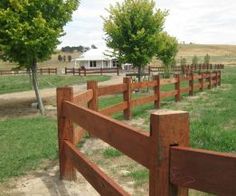 a wooden fence in the middle of a grassy field