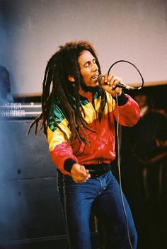 a man with dreadlocks singing into a microphone