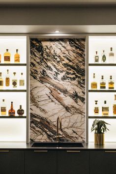 a kitchen with marble counter tops and shelves full of liquor bottles on the wall behind it