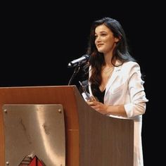 a woman standing at a podium in front of a microphone