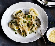 a white plate topped with pasta and broccoli next to a bowl of cheese