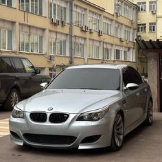 a silver car parked in front of a tall building