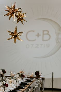 a long table is set with black and white plates, silverware, and gold star decorations