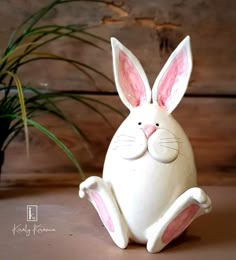 a ceramic rabbit sitting next to a potted plant