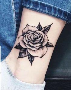 a black and white rose tattoo on the ankle