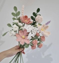 a person holding a bouquet of flowers with crocheted stems and leaves in their hands