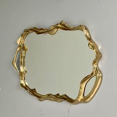 a mirror that is sitting on top of a white wall with gold trimmings