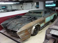 an old car that is being worked on in a garage with other cars behind it