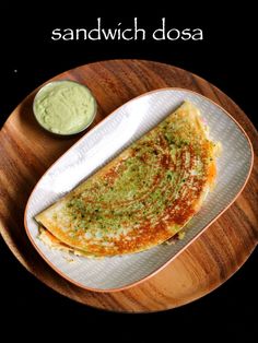 an omelet on a white plate with a small bowl of green sauce next to it