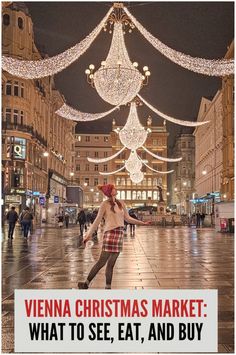 a woman is dancing in the middle of a street with christmas lights hanging above her