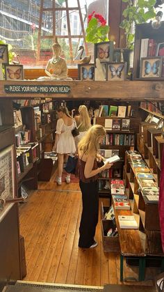 two women are looking at books in a book store while another woman is standing behind them