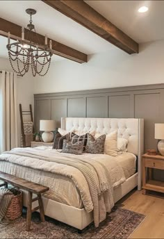 a large bed sitting under a chandelier in a bedroom next to a window