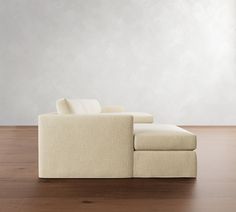 a couch sitting on top of a wooden floor next to a white wall and window